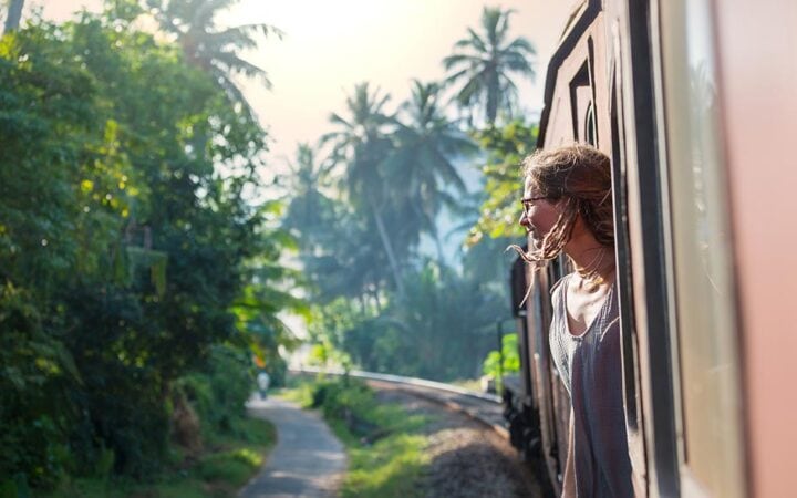 Young woman on a scenic train ride in Sri Lanka, highlighting travel and safety.
